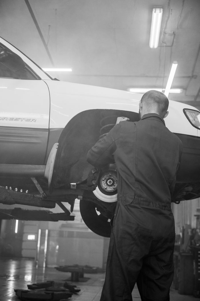 Mastering the First Impression: Your intriguing post title goes here A mechanic fixing a car in an indoor repair shop setting, black and white photo.